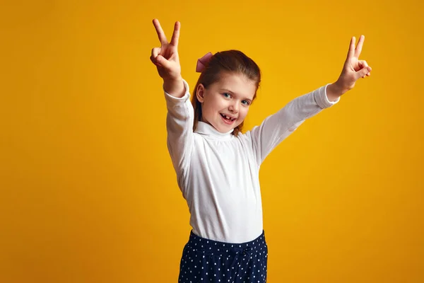 Menina mostrando gesto de paz com ambas as mãos levantadas contra fundo amarelo — Fotografia de Stock