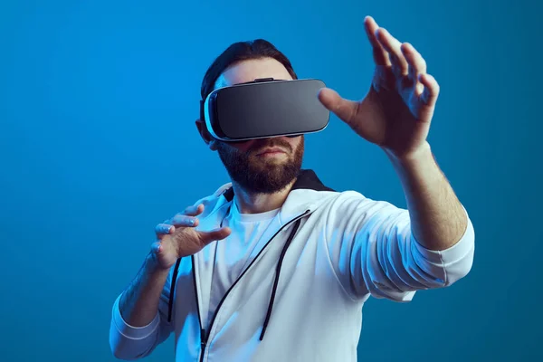 Bearded man trying VR headset and exploring another world isolated on blue — Stock Photo, Image