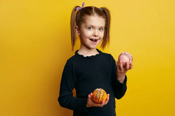 Heyecanlı kız gülümsüyor ve sarıya karşı çikolata bombası tutuyor. 
