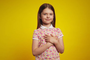 Kız avuçlarını kalbinde tutar, minnettarlığını, memnuniyetini ve minnettarlığını ifade eder.