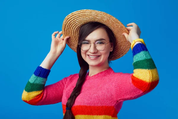 Attraktiv kvinna ler och bär regnbåge tröja, hatt och glasögon — Stockfoto