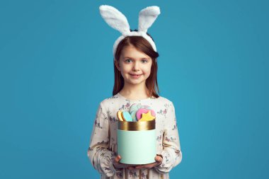 Sevimli kız elinde kurabiye kutusuyla, tavşan kulağı takıyor ve güzel elbiseler giyiyor.