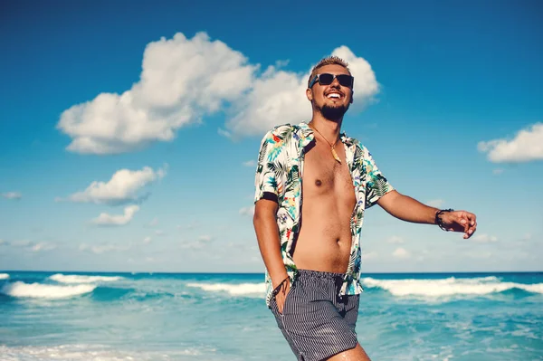 Jóképű férfi hawaii ingben a tengeren vagy az óceán hátterében. — Stock Fotó