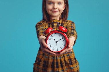 Bulanık küçük kız kameraya kırmızı alarmlı saat gösteriyor