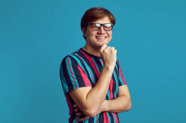 Neşeli adamın düşünceli, neşeli bir yüzü var. Elini çenenin altında tutuyor.