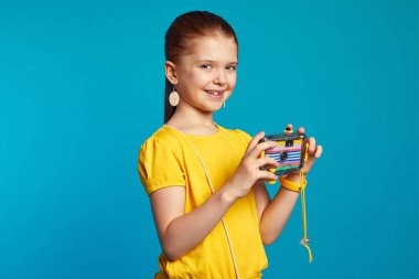 Heyecanlı çocuk fotoğrafçı mavi üzerinde tek başına dururken kamerayı tutuyor.