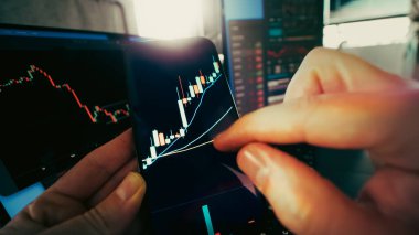 Kripto para birimi şamdan şeması akıllı telefon alım-satım büyüme analizi. Eller arka planda mali gösterge paneli olan mobil ekranda gösterilen boğa gibi şamdan grafiğine zumluyor. Kripto para birimi rallisi, piyasa yükselmesi ve teknik t kavramı