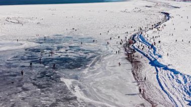 Donmuş kum tepeleri kışın kışın hava sahnesi. Drone görüntüleri kar kaplı kum tepeleri buzlu kıyı yürüyüşçüleri sunuyor. Donmuş su yüzeyi kış turizmi mevsimsel Polonya manzarasını keşfediyorlar.
