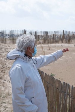 Yaşlı bir kadın Brittany sahilinde yürüyor.