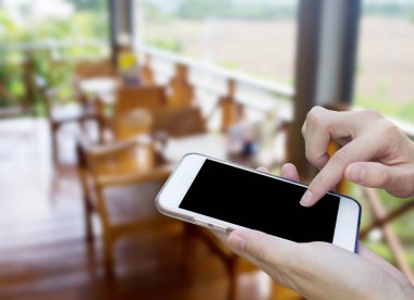 Cep telefonu dokunmatik ekran ile kahve dükkanı bulanıklık geri kullanan kadın