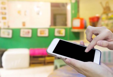 Cep telefonu dokunmatik ekran ile kahve dükkanı bulanıklık geri kullanan kadın