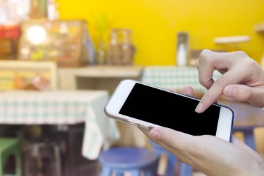 Cep telefonu dokunmatik ekran ile kahve dükkanı bulanıklık geri kullanan kadın