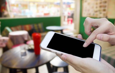 Cep telefonu dokunmatik ekran ile kahve dükkanı bulanıklık geri kullanan kadın