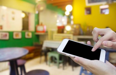 Cep telefonu dokunmatik ekran ile kahve dükkanı bulanıklık geri kullanan kadın