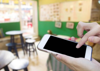 Cep telefonu dokunmatik ekran ile kahve dükkanı bulanıklık geri kullanan kadın