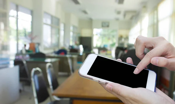 Woman using touch screen mobile phone with blur office