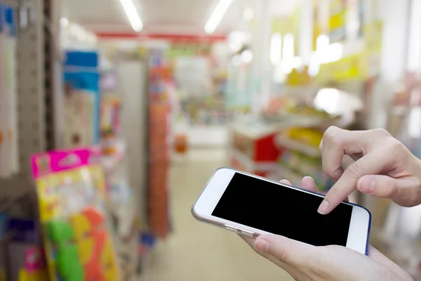 Woman using touch screen mobile phone with blur shopping mall