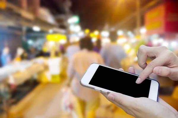 Mujer usando la pantalla táctil del teléfono móvil con la noche borrosa Mercado —  Fotos de Stock