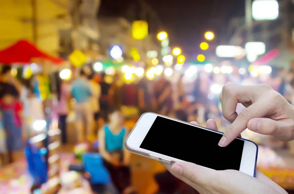 Mujer usando la pantalla táctil del teléfono móvil con la noche borrosa Mercado — Foto de Stock