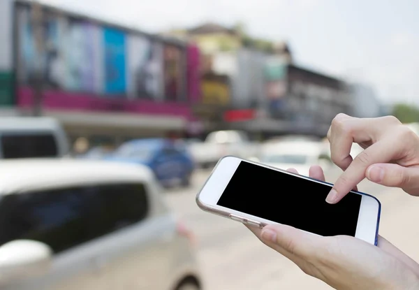 Kobieta za pomocą ekran dotykowy telefon z rozmycie ruchu samochodów na t — Zdjęcie stockowe