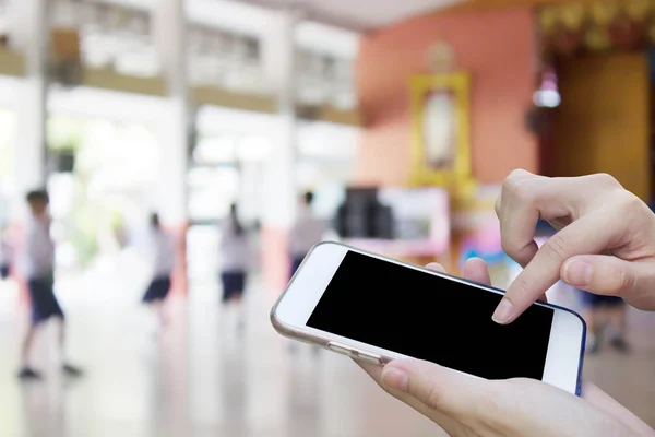 Mujer usando el teléfono móvil de pantalla táctil con desenfoque de playi estudiante — Foto de Stock