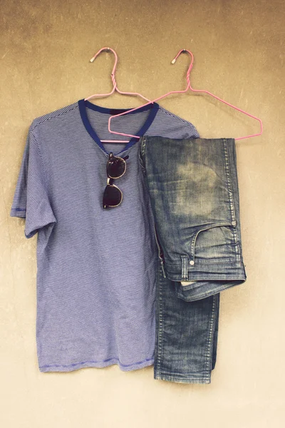 Jeans,T-shirt and sunglasses hanging on the wall — Stock Photo, Image