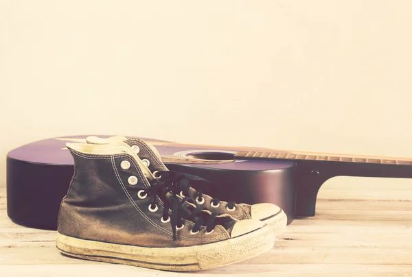 Tom vintage: guitarra, tênis na mesa de madeira — Fotografia de Stock