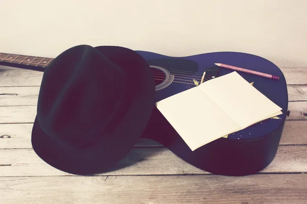 Tom vintage: guitarra, chapéu, livro, lápis sobre mesa de madeira — Fotografia de Stock