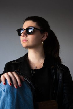 Deri ceket ve güneş gözlüğü takan modern sarışın milenyum. Yaşam tarzı blogları ve modern sokak kıyafetleri promosyonları için harika..