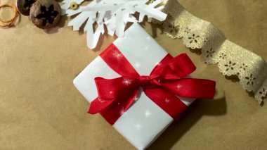 Beyaz kağıtta Noel hediyesi, el sanatları tedarikçileri arasında geçiyor. Malzeme bakımı ve geri dönüşüm kavramı. Noel veya yeni yıl için el yapımı hediyeler. Yavaşça yakınlaştır