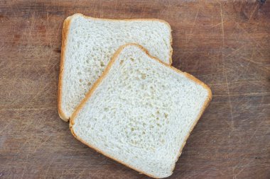 Düz beyaz ekmek parçaları basit bir ahşap tabakta duruyor. Sağlıklı kahvaltıların reklamını yapmak için ideal..