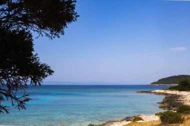 Proizd Adası kıyı şeridi turkuaz mavisi Adriyatik Denizi 'ni ve güneşli kayalık plajları berrak bir yaz gökyüzü altında sunuyor.
