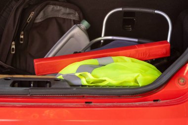 Yansıtıcı yelek, uyarı üçgeni, motor yağı ve sırt çantası ile dolu bir araba bagajı. Yolculuk, arıza ve uzun yolculuklar için gerekli güvenlik kiti.