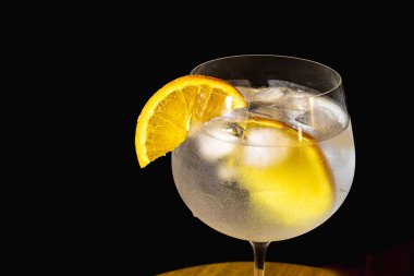 Portakal dilimli cin tonik kokteyli ve yaz partileri için soğuk ve meyveli içecek konsepti. Fotoğraf: 45 derece. Mesaj için yer var. Dramatik ışık