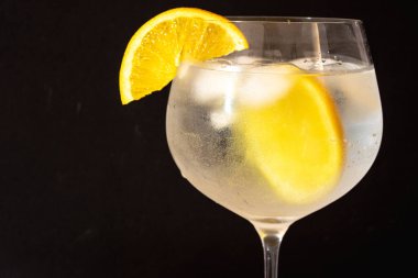 Kök bardakta cin tonik kokteyli, parlak bir portakal dilimi ve erimiş buz, yaz partileri için soğuk ve meyveli bir içecek konsepti sunuyor.