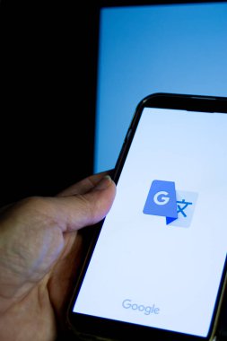 Smartphone ekranı google uygulama simgesini gösterir, anında çokdilli çeviri, ai-güçlü dil araçları sembolize eder, ve seyahat, iş ve öğrenme için kusursuz küresel iletişim