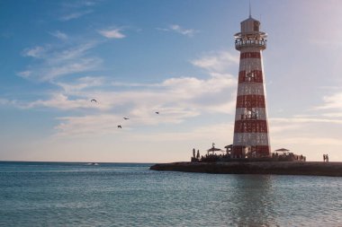 Okyanus Koyu deniz feneri sakin denizin yanında duruyor, günbatımında sakin bir Karayip manzarası yaratıyor. Tropikal seyahat yeri ve gemi seyahati