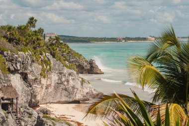 Tulum kalıntıları el değmemiş bir Karayip plajının üzerindeki kayalıklarda duruyor. Titrek turkuaz denizi çevreleyen gür palmiyeler ve altın kumda kopan dalgalar antik tarihi ve tropikal güzelliği gözler önüne seriyor.
