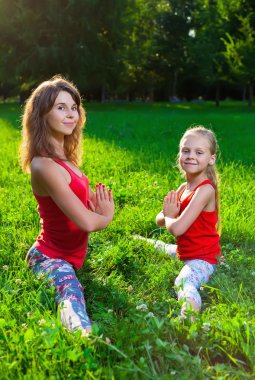 Anne ve kızı açık havada yoga yaparken