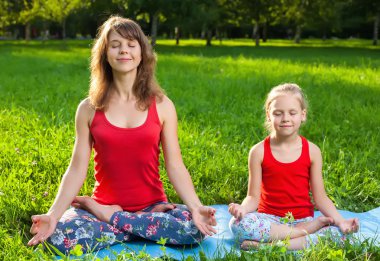 Anne ve kızı açık havada yoga yaparken