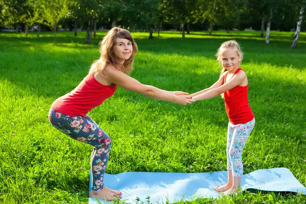 Matka i jej córka na zewnątrz robi joga — Zdjęcie stockowe