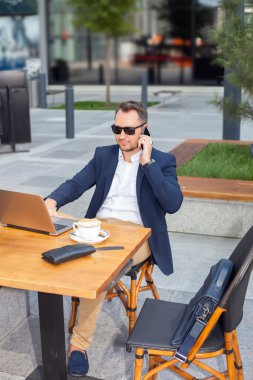 Dizüstü bilgisayar, çalışma işadamı cep telefonundan konuşuyor