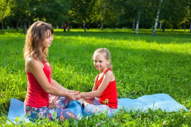 Anne ve kızı açık havada yoga yaparken