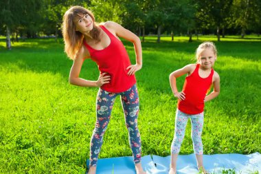 Anne ve kızı açık havada yoga yaparken