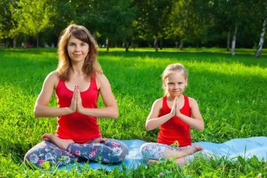 Anne ve kızı açık havada yoga yaparken