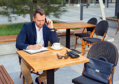 Dizüstü bilgisayar, çalışma işadamı cep telefonundan konuşuyor