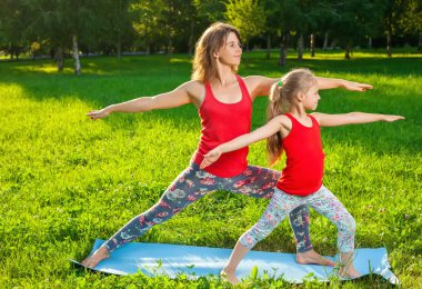 Anne ve kızı açık havada yoga yaparken