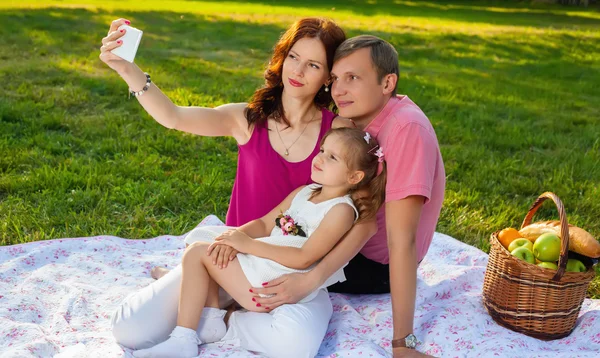 Jovem família feliz fazendo piquenique no prado — Fotografia de Stock