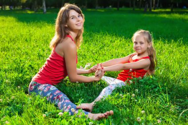 Anne ve kızı açık havada yoga yaparken