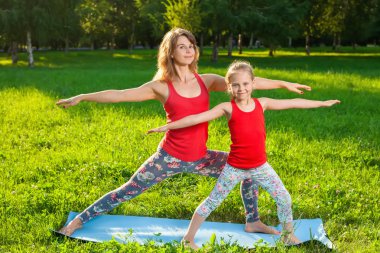 Anne ve kızı açık havada yoga yaparken
